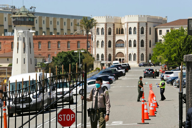 FILE - In this July 9, 2020 file photo, a correctional officer closes the main gate at San Quentin State Prison in San Quentin, Calif. On Saturday, Sept. 26, 2020, Gov. Gavin Newsom signed a law that requires the state to house transgender prisoners based on their gender identity. The law does have an exception for “management or security concerns.” (AP Photo/Eric Risberg, File)